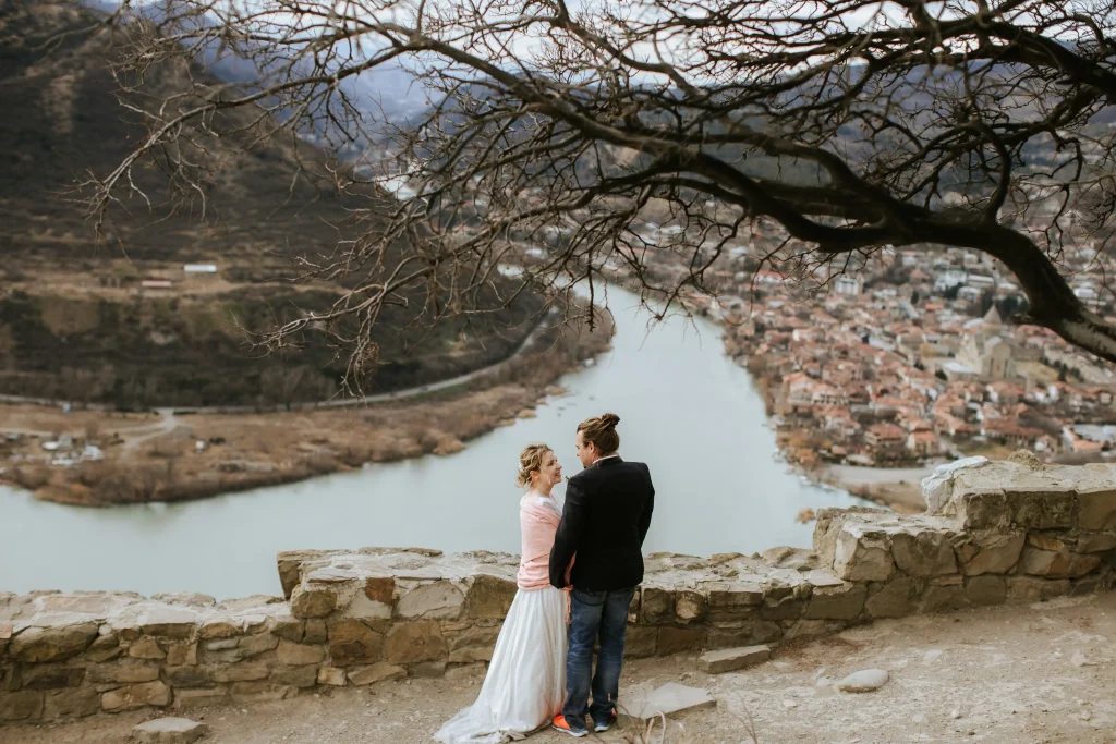 Молодожёны-геофизики во время свадебной церемонии в горах Грузии, на фоне слияния рек и старого города Мцхета