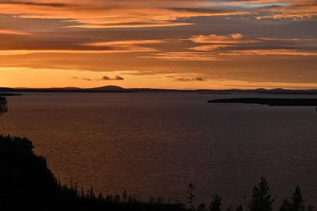 Закат над озером на Кольском полуострове, отражающим тёплые цвета вечернего неба