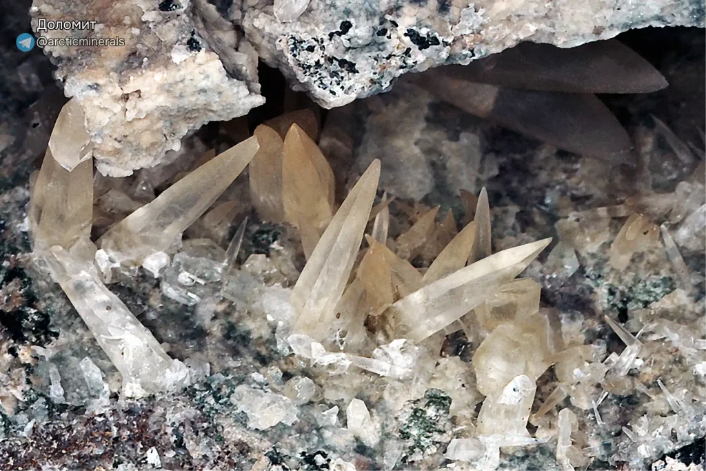 Макросъемка кристаллов доломита. Удлиненные полупрозрачные кристаллы с бледно-желтым оттенком, растущие в полости горной породы