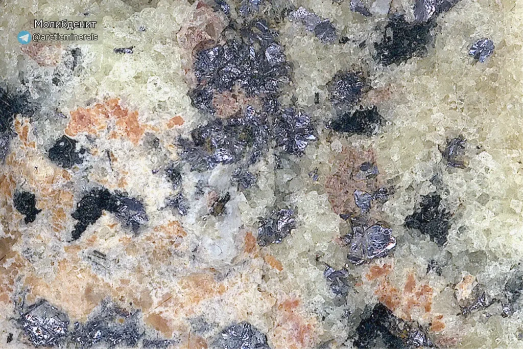 Макросъемка молибденита. Блестящие серебристо-серые вкрапления молибденита в зернистой породе с кремнистыми, белыми и буроватыми участками