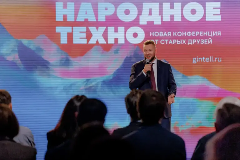 Борис Курцев выступает на конференции 'Народное Техно' перед аудиторией, на фоне большого экрана с надписью Народное Техно.