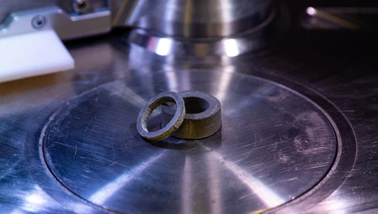 Два круглых магнита, напечатанных на 3D-принтере, лежат на металлической поверхности