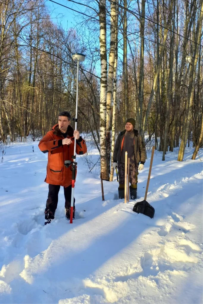 Геофизики проводят измерения в заснеженном лесу с использованием геодезического и геофизического оборудования