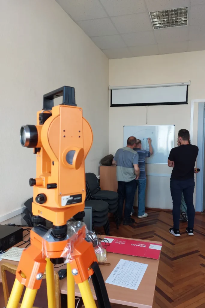 Практическое занятие по геодезии: теодолит на штативе и обсуждение схемы у доски