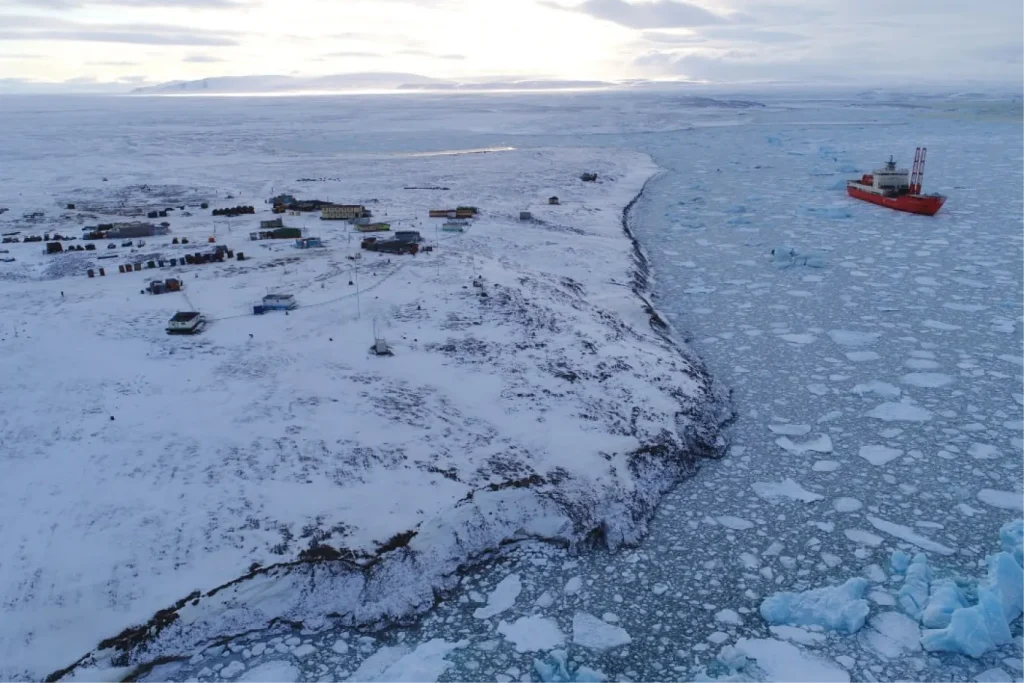 Арктическая база на побережье, окружённая льдом и морем с дрейфующими льдинами