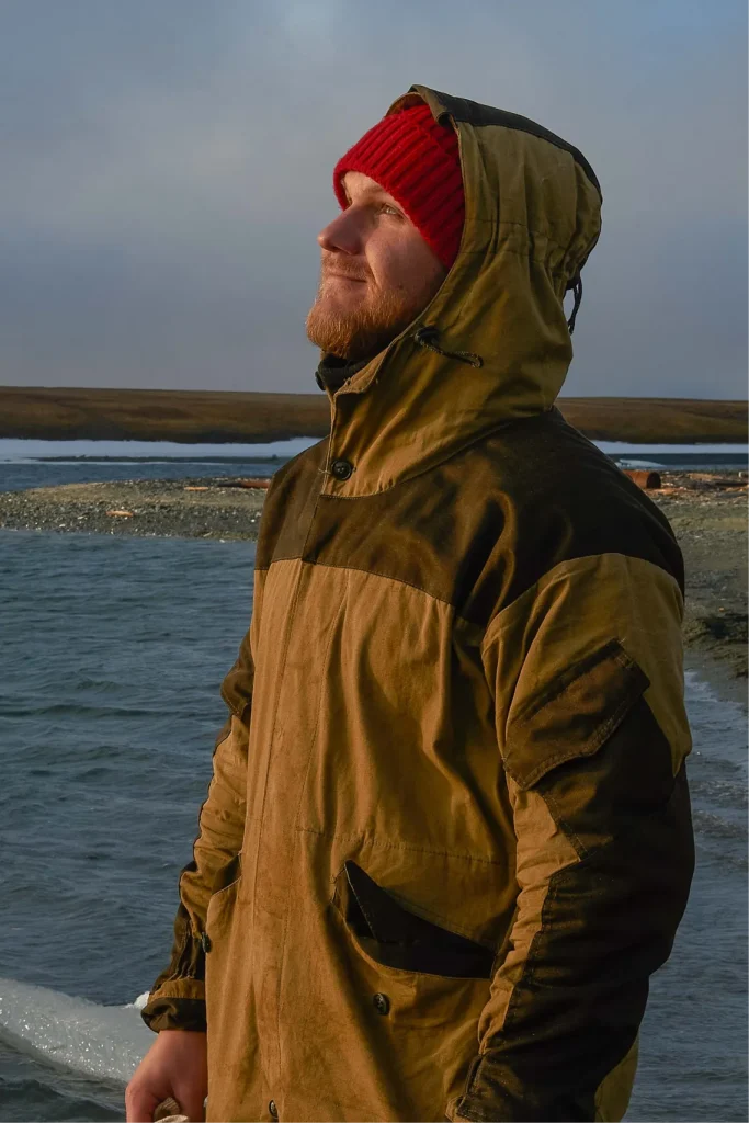 Инженер-геофизик в зимней куртке у берега северного моря во время полевых работ