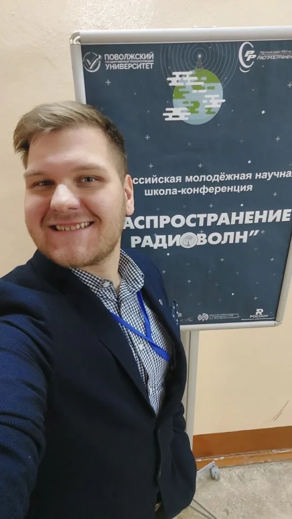 Глеб Загорский на фоне постера Всероссийской молодёжной конференции «Распространение радиоволн»
