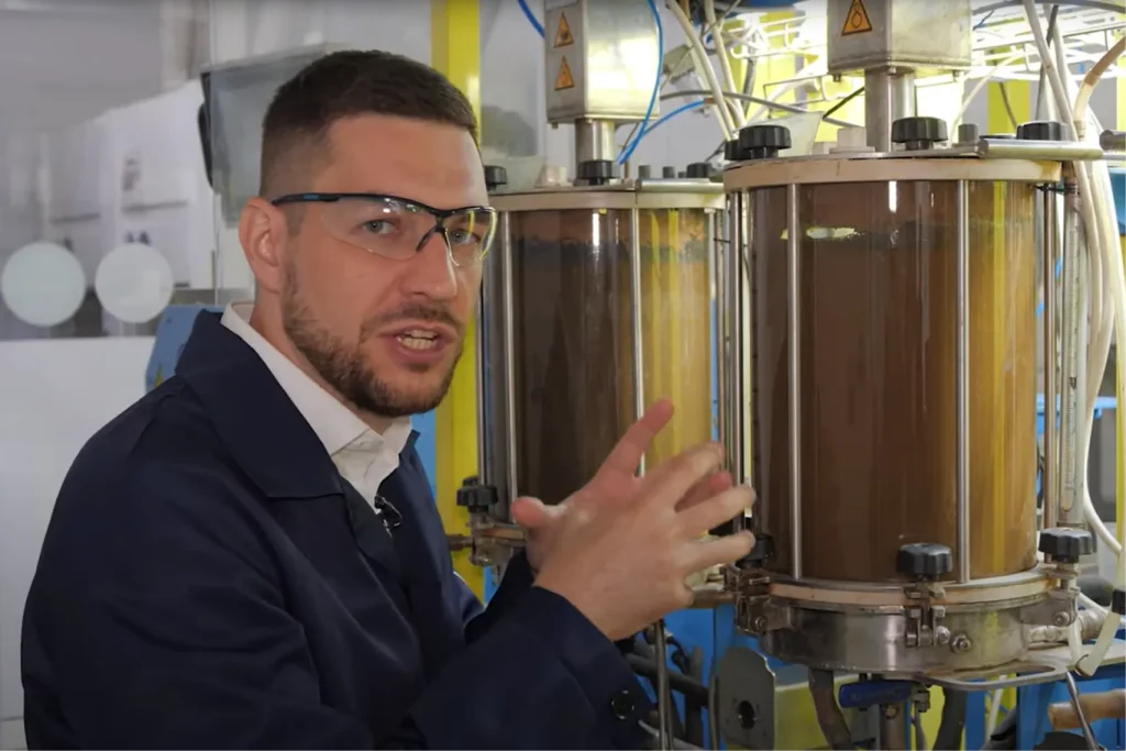 Геолог Исхак Фарахутдинов у лабораторной установки, объясняет процесс бактериального окисления для извлечения упорного золота