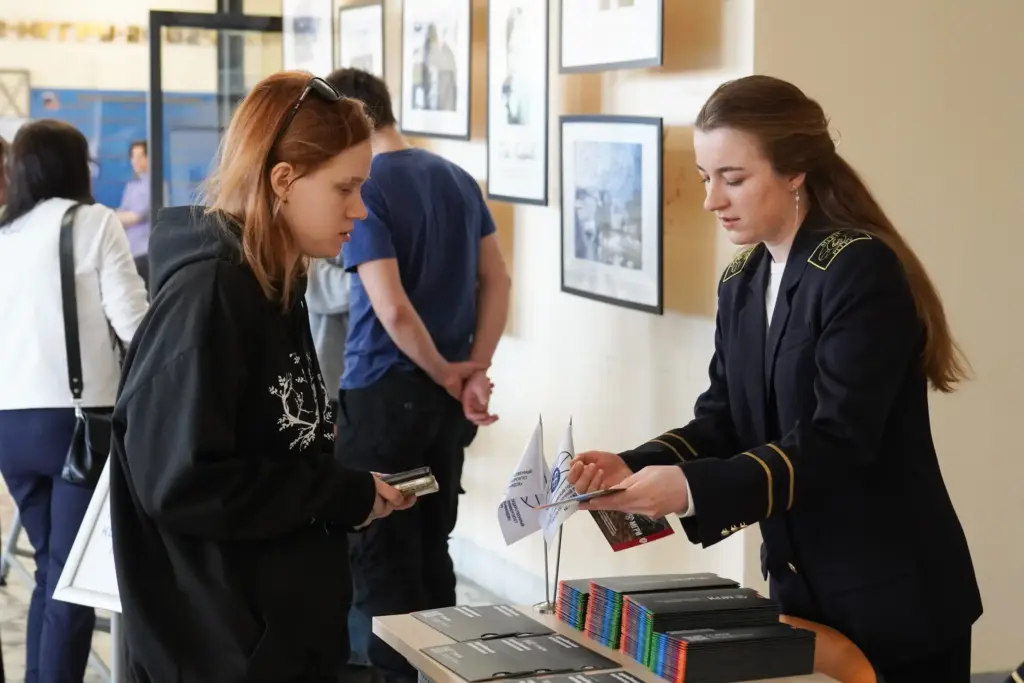 Студентка в форме рассказывает абитуриентке о факультетах и программах вуза на дне открытых дверей