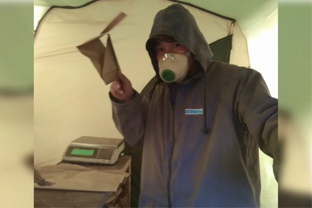 Геолог в защитной маске подготавливает пробы к отправке.