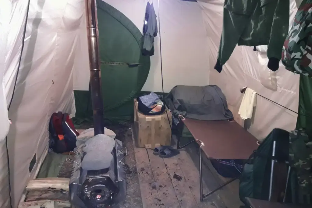Внутри жилой палатки: раскладушка, печка и минимум удобств — всё, что нужно для отдыха после маршрута