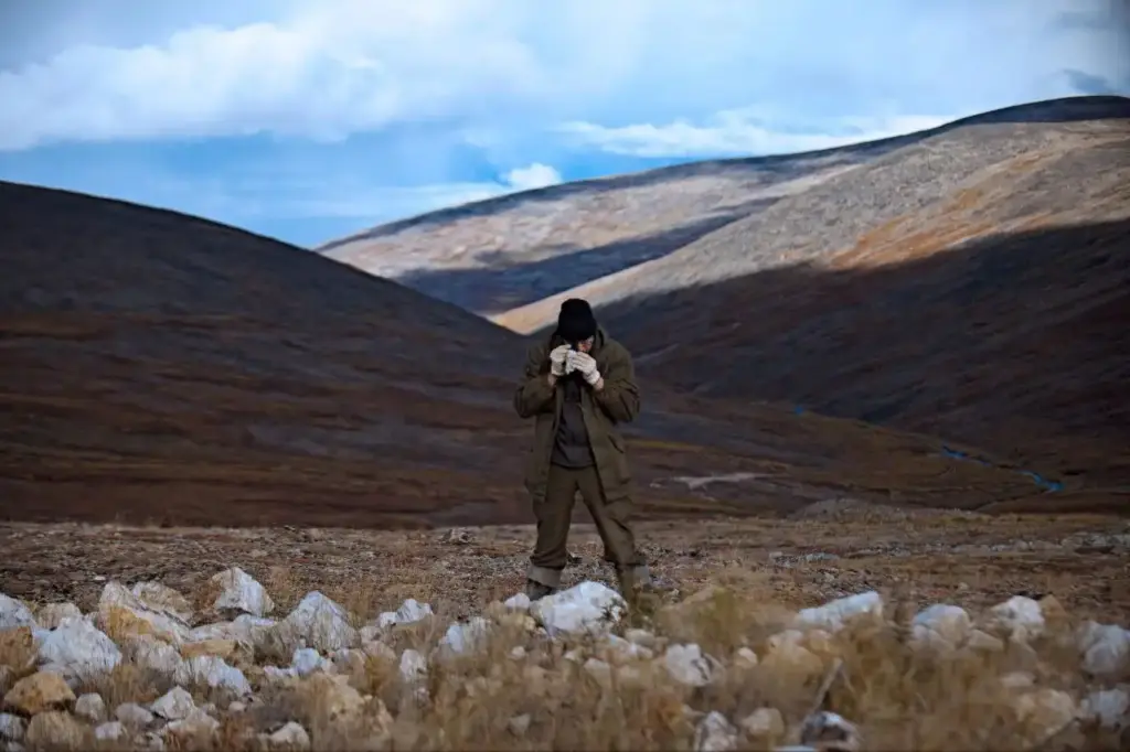 Геолог рассматривает породу на склоне в горах во время экспедиции