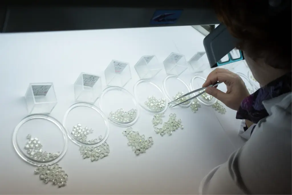 Сотрудница сортирует алмазы в лабораторных условиях после обогащения