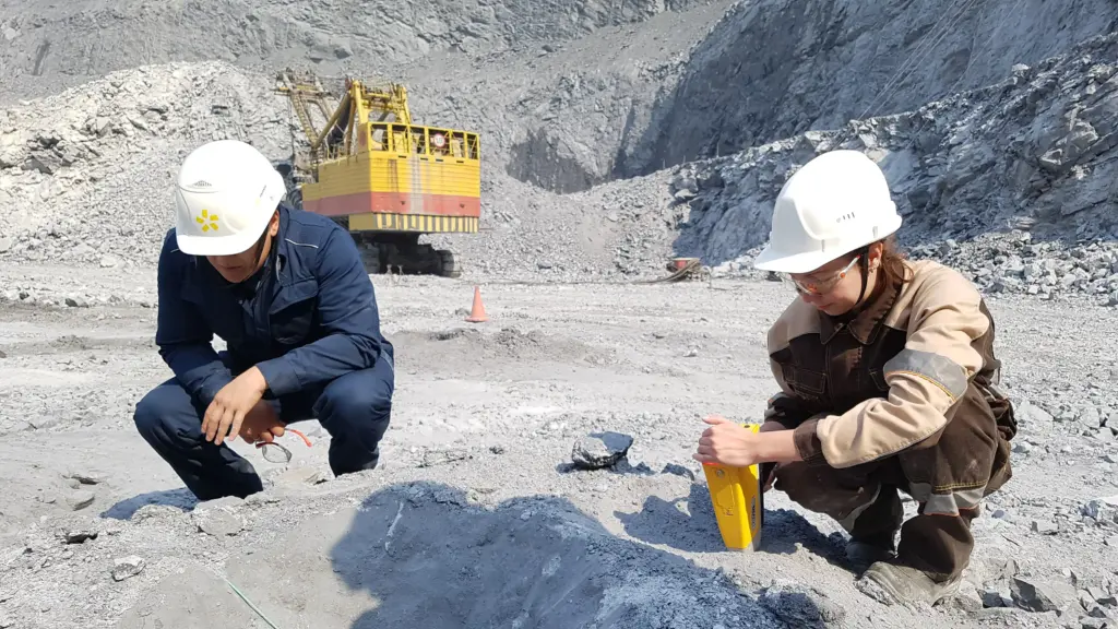 Геологи проводят контроль буровзрывных работ в карьере. На заднем плане — экскаватор-драглайн на горном участке