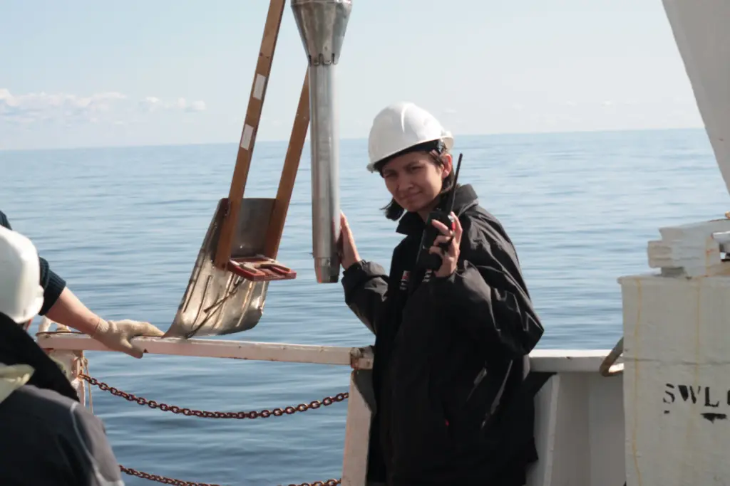 Женщина в каске на палубе исследовательского судна управляет процессом отбора донных осадков во время морских геолого-геофизических изысканий