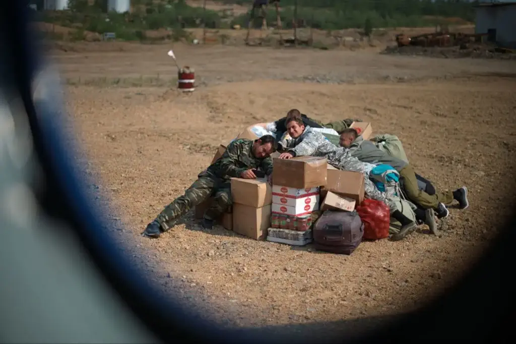 Группа геологов отдыхает на коробках с провиантом и снаряжением во время заброски на участок в труднодоступном районе