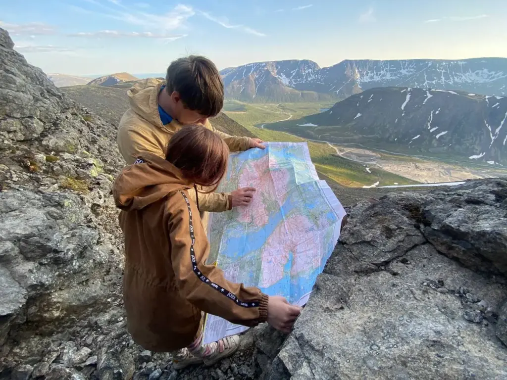 Молодые геологи с топографической картой в полевых условиях. Геологическая работа начинается с маршрутов, описания пород и составления карт