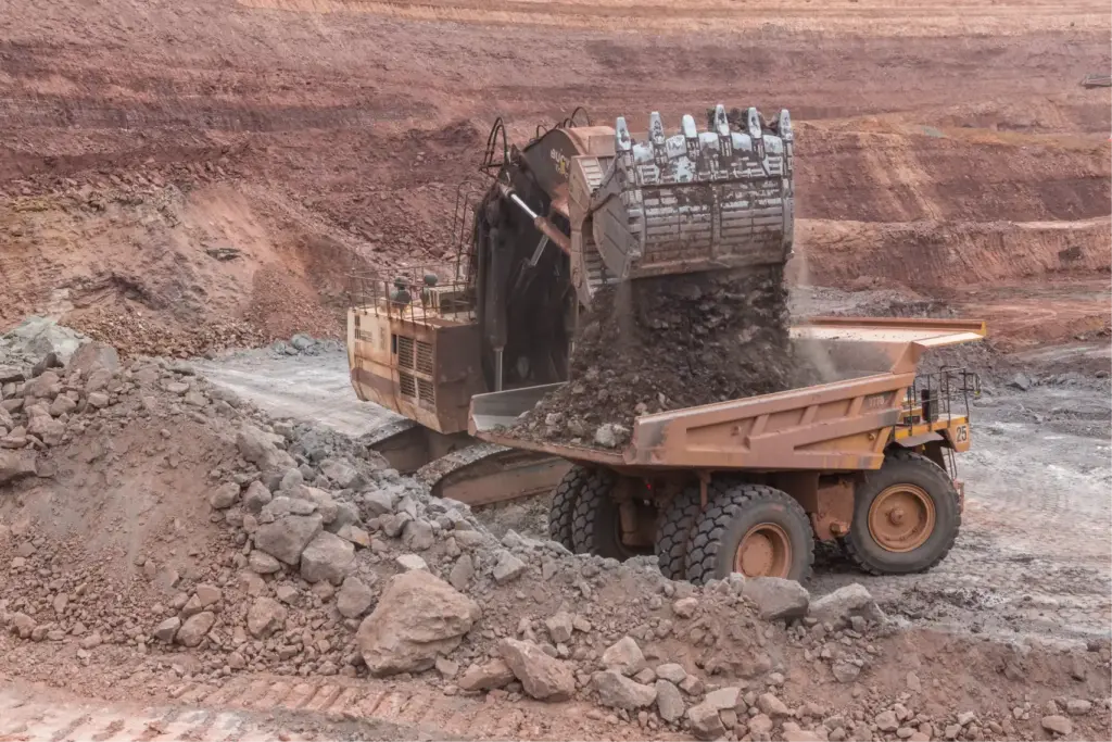 Погрузка горной массы в карьерный самосвал — экскаватор загружает породу в кузов крупнотоннажного самосвала на алмазном карьер