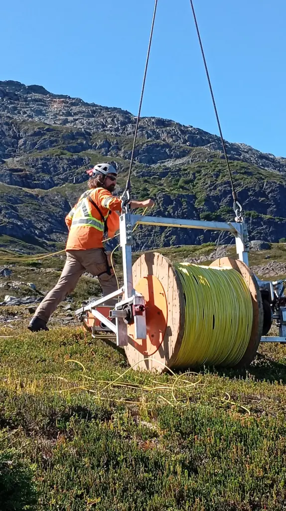 Электромагнитные исследования: геофизик закрепляет провод на земле перед тем, как вертолёт начнёт разматывать катушку и формировать передающую петлю